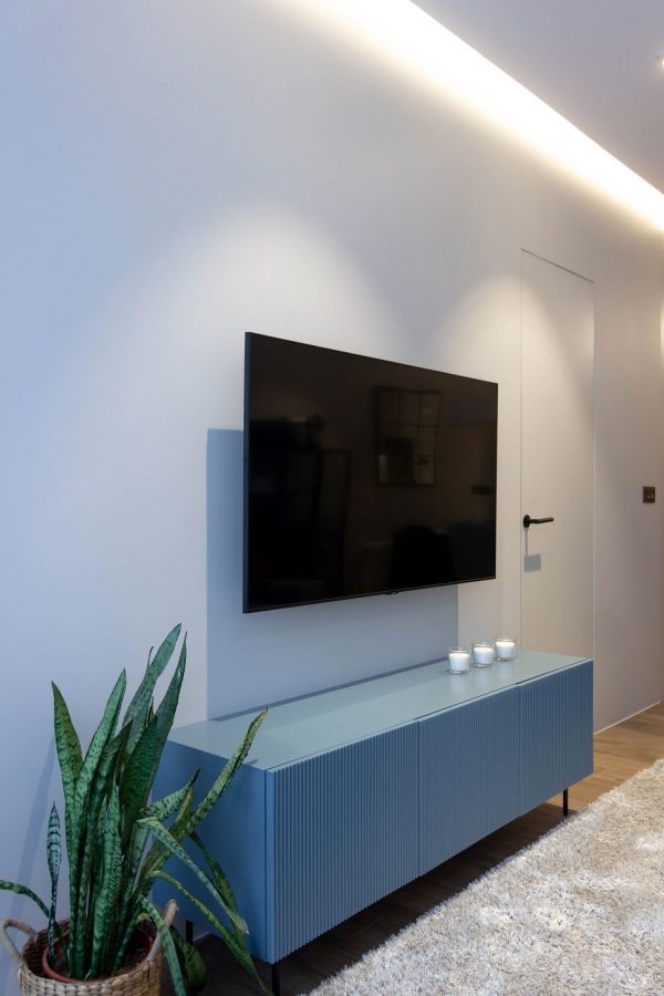 Salón con mueble de televisión a medida en tono azulado — Reformas Compás
